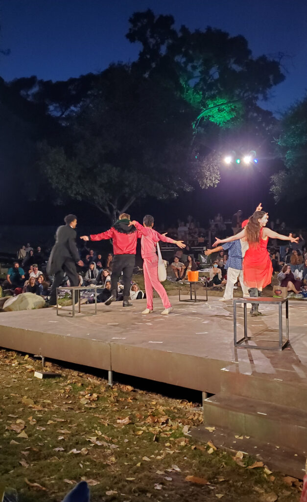 close up of the stage front row at griffith park with people in costumes, arms spread wide.