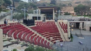 Curved rows of red theater seats in an outdoor amphitheater at Getty Villa with hillside and trees in background