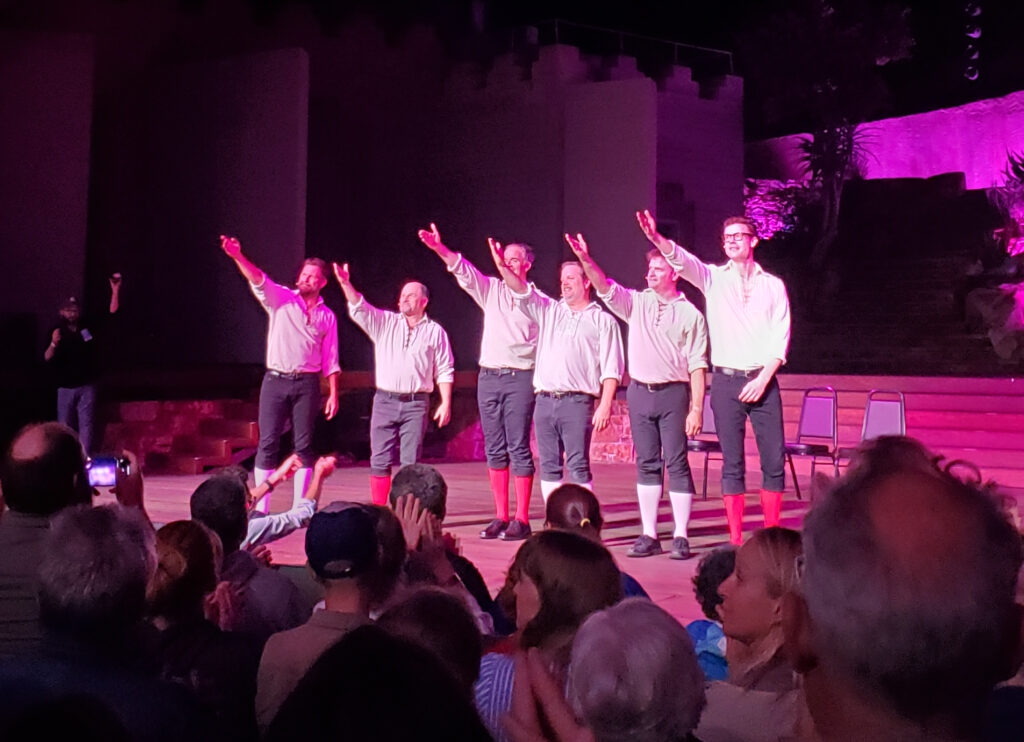 the improv shakespeare troupe plus actor jason alexander - six men in classical white shirts and black slacks and stockings, on stage at the ford at night