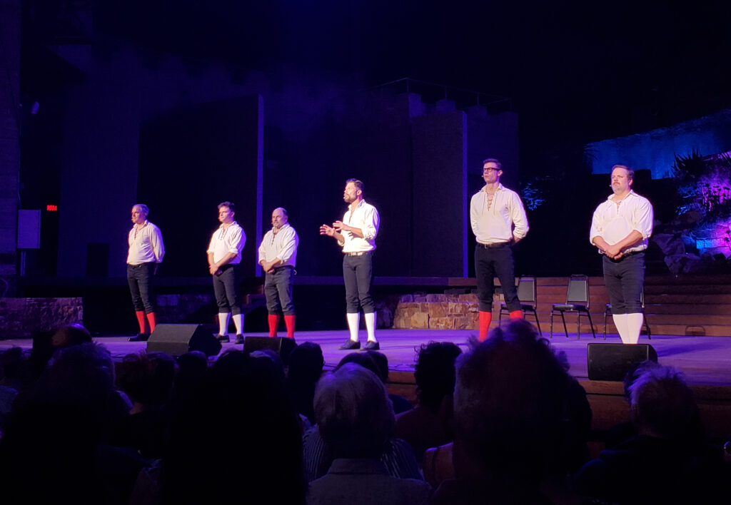 the improvised shakepeare co on stage at the ford theater as night sets, spotlights on them