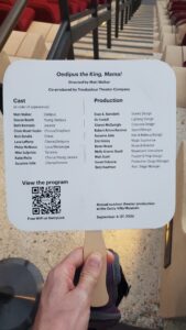 Hand holding a theater fan listing cast and production crew for Oedipus the King Mama at the Getty Villa outdoor theater in September 2025